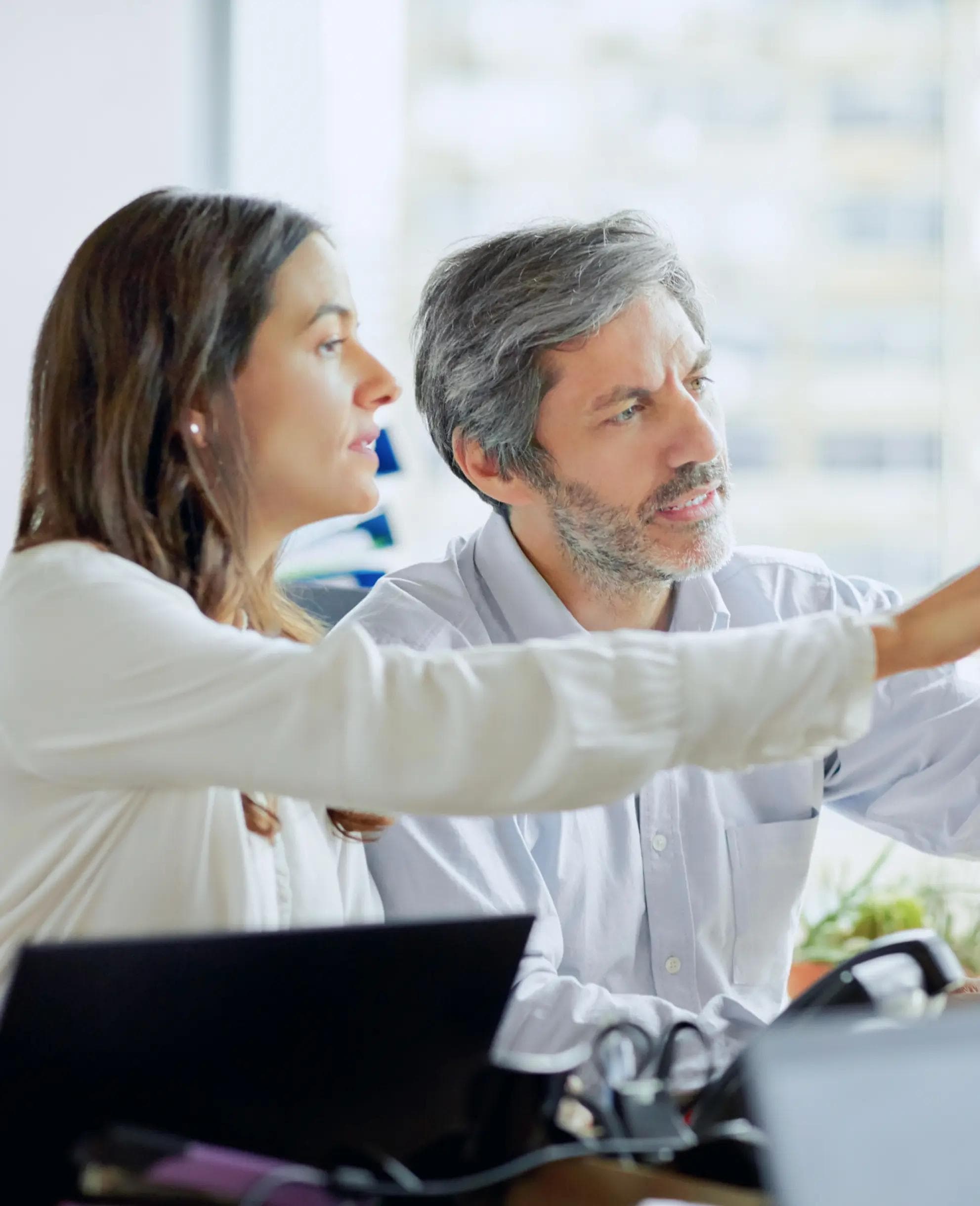 Image of two people look at a screen and pointing.