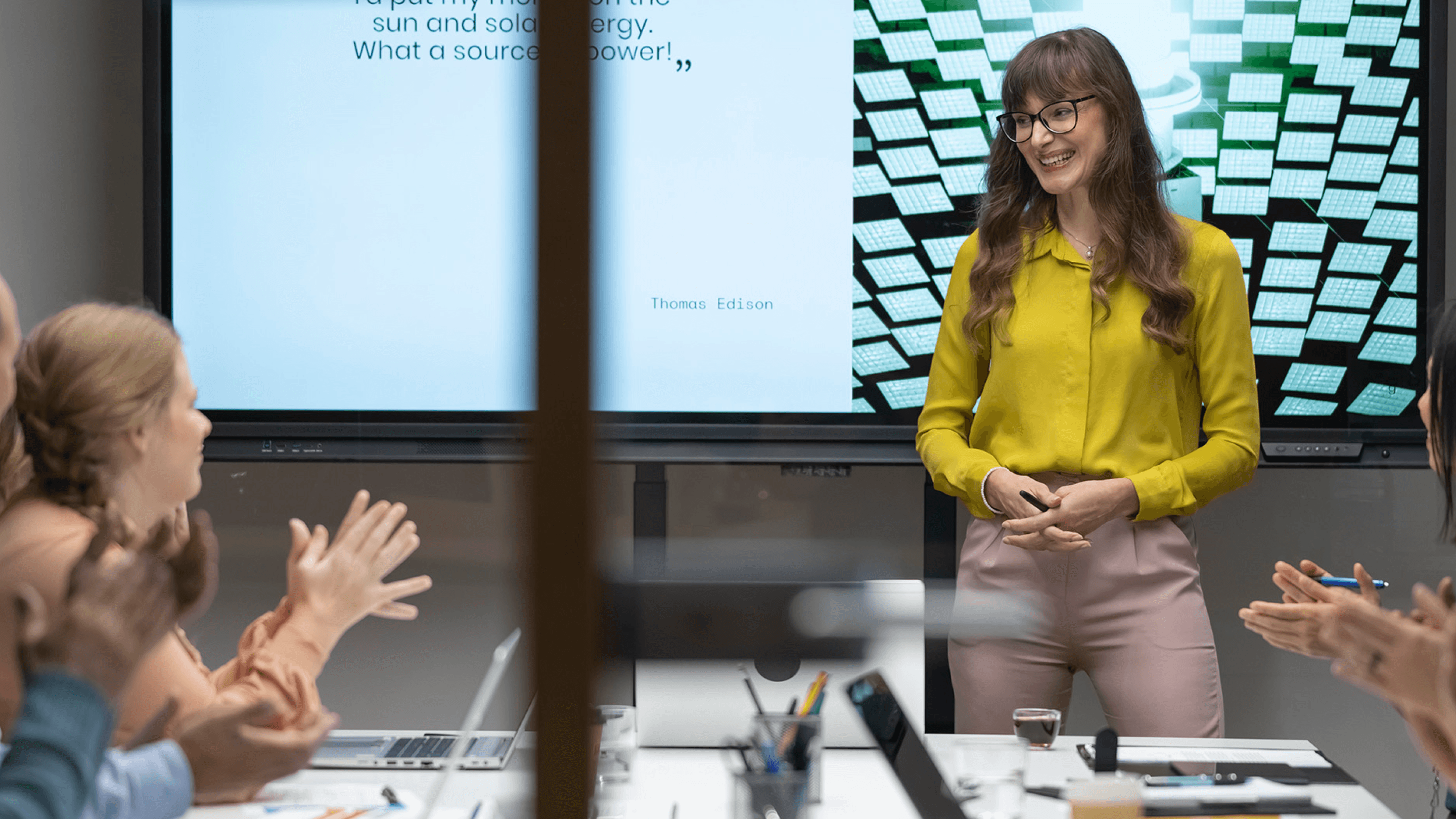 Women smiling while presenting in a conference room.