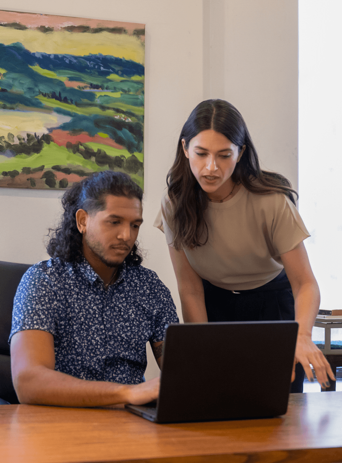 Women standing next to man while looking at a laptop.