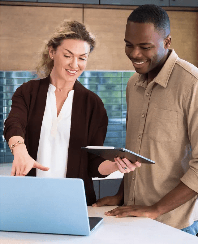 Man and women smiling while looking at laptop.