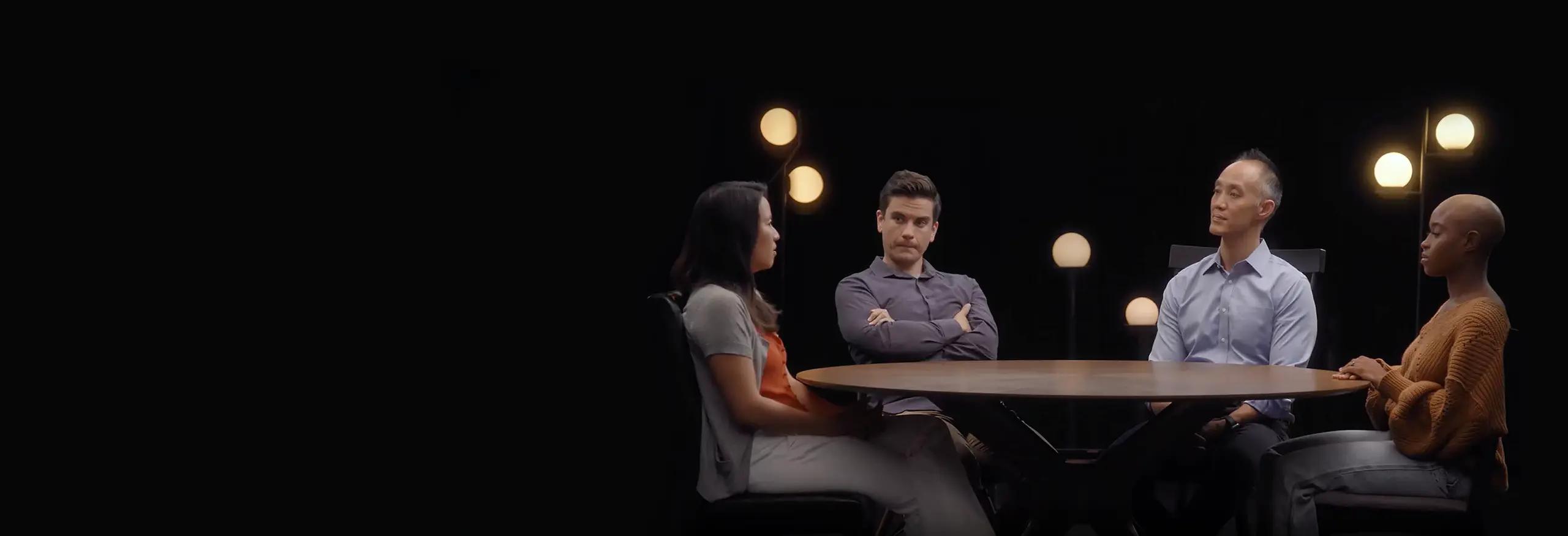 Image of four people sitting at a table having a discussion.
