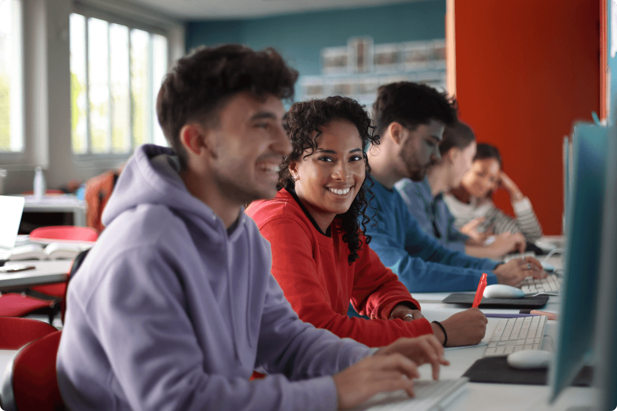 Students smiling while typing on computers.
