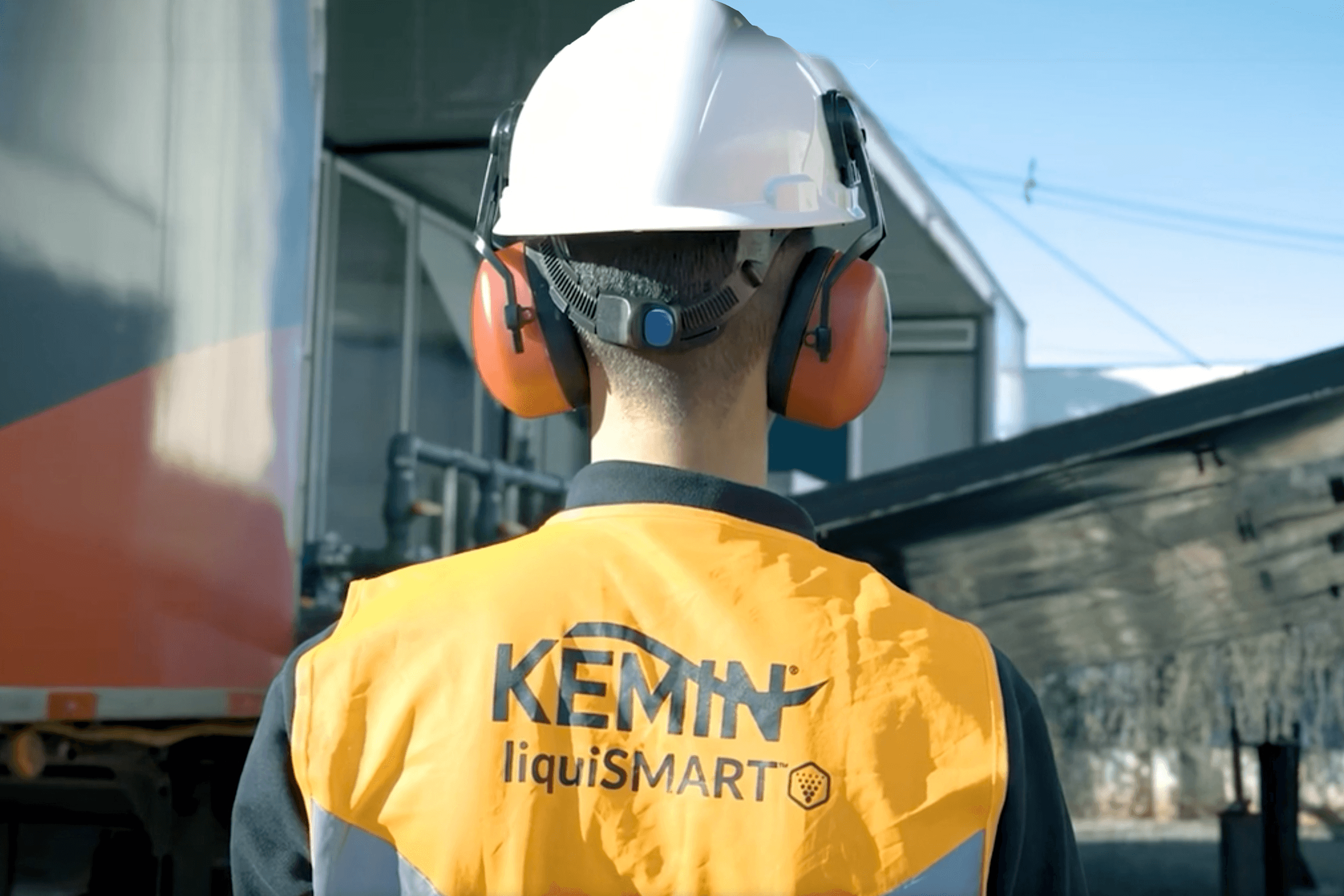 A man wearing ear muffs and a vest that says Kemin liquismart.